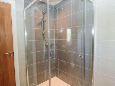 A bathroom with a glass shower enclosure and tiled walls at Rose Lodge in High Newton-by-the-Sea near Embleton