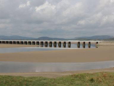 A long bridge over a river with sandy banks and grassy foreground at Walkers Rest in Warton near Carnforth