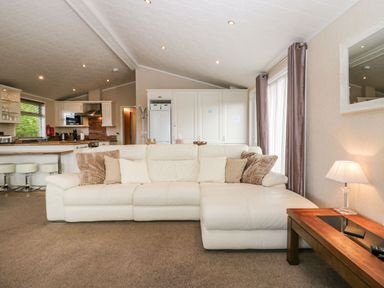 A living room with a white sofa and cushions next to a wooden coffee table with a lamp at Walkers Rest in Warton near Carnforth