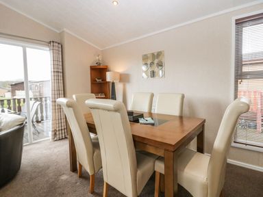 A dining room with six chairs around a wooden table with a glass panel in the center at Walkers Rest in Warton near Carnforth