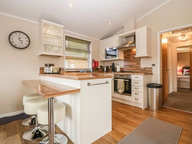 A kitchen with wooden countertops stools oven microwave and a clock on the wall at Walkers Rest in Warton near Carnforth