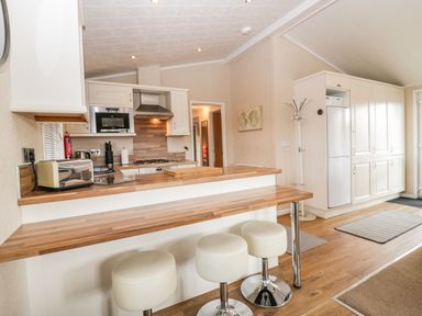 A kitchen with a countertop breakfast bar and stools a refrigerator and cabinets at Walkers Rest in Warton near Carnforth