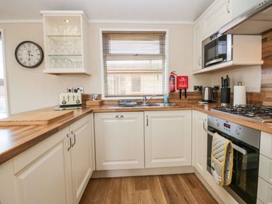 A kitchen with wooden countertops a sink a gas stove oven microwave kettle and clock at Walkers Rest in Warton near Carnforth
