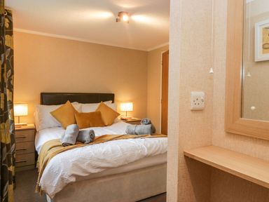 A bedroom with a bed with cushions and rolled towels and lamps on side tables at Walkers Rest in Warton near Carnforth