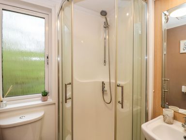 A bathroom with a glass shower enclosure a toilet sink and a frosted window at Walkers Rest in Warton near Carnforth