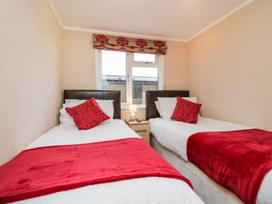 A bedroom with two single beds red cushions and throws a lamp on a small table between the beds at Walkers Rest in Warton near Carnforth