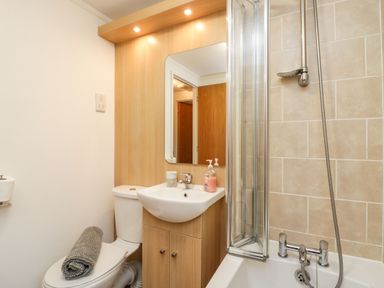 A bathroom with a toilet a sink with a mirror a shower and a bathtub at Walkers Rest in Warton near Carnforth
