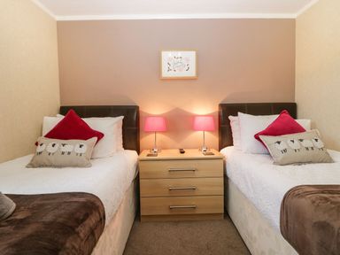 A bedroom with two single beds a bedside table with two lamps and a wall decoration at Walkers Rest in Warton near Carnforth