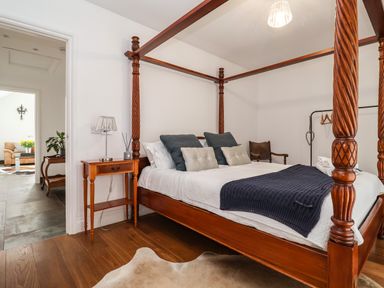 A bedroom with a wooden four-poster bed and a bedside table with a lamp and diffuser at Polly's Annexe in Levington