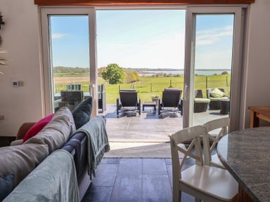 A living room with a view of the patio and landscape at Polly's Annexe Levington