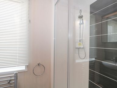 A bathroom with a window with blinds a towel ring a shower enclosure and a mirror at The Olive Lodge 227 Sycamore in New Milton