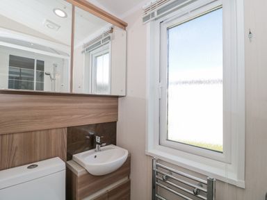 A bathroom with a sink toilet mirror window and towel radiator at The Olive Lodge 227 Sycamore in New Milton