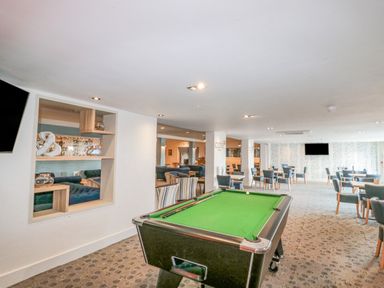 A recreation room with a pool table and seating area with tables and chairs at The Olive Lodge 227 Sycamore in New Milton