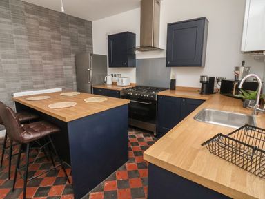 A kitchen with wood countertops a stove a sink and bar stools at The Old Station House in Withernsea