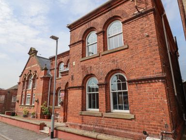 A red brick building with arched windows and potted plants outside at The Old Station House in Withernsea