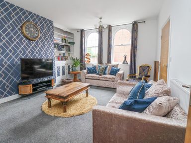 A living room with two sofas a wooden coffee table and television at The Old Station House in Withernsea