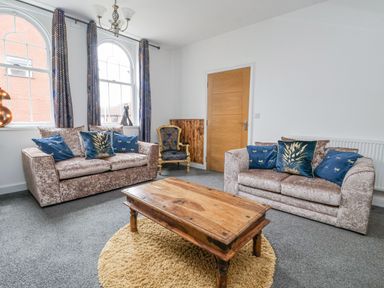 A living room with two sofas a wooden coffee table and a blue armchair at The Old Station House Withernsea