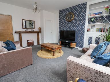 A living room with two sofas a wooden coffee table a television on a stand and a wall clock at The Old Station House in Withernsea