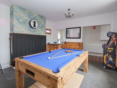 A game room with a blue pool table wooden paneling and an arcade machine at The Old Station House in Withernsea