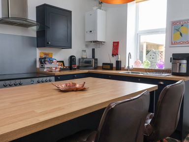 A kitchen with wooden countertops a stove coffee maker and window at The Old Station House in Withernsea