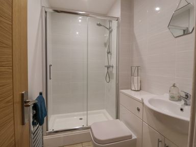 A bathroom with a shower enclosure a toilet a sink with a cabinet and a towel on a rack at The Old Station House in Withernsea