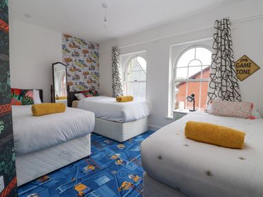 A bedroom with three single beds and a blue carpet with cartoon characters at The Old Station House in Withernsea