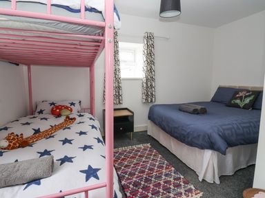 A bedroom with a pink bunk bed and a double bed with blue bedding at The Old Station House in Withernsea