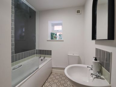 A bathroom with a bathtub a sink a toilet and a small window at The Old Station House in Withernsea