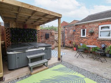 An outdoor patio area with a covered hot tub wooden steps and a small table with three chairs at The Old Station House in Withernsea