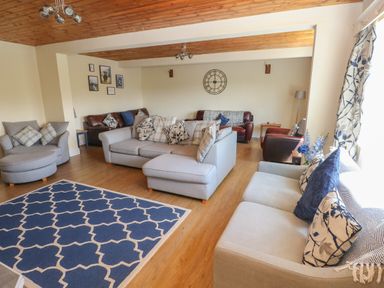 A living room with multiple sofas and armchairs a blue patterned rug and wall decorations at Hillside Lodge in Newtown