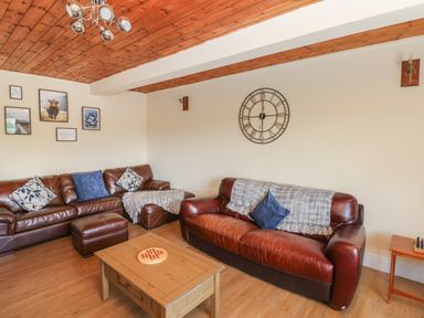 A living room with brown leather sofas a wooden coffee table and a wall clock at Hillside Lodge in Newtown