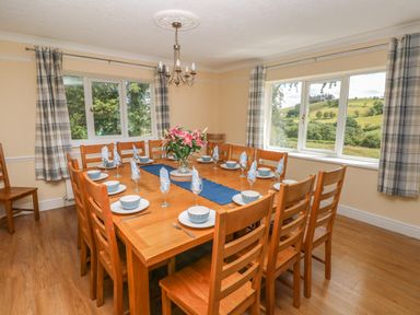A dining room with a large wooden table set for twelve with blue bowls and napkins and flowers on the table at Hillside Lodge in Newtown