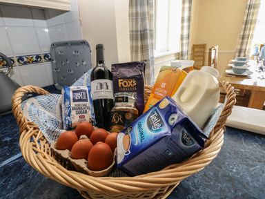 A wicker basket with eggs sugar coffee wine milk orange juice and tea on a kitchen counter at Hillside Lodge in Newtown