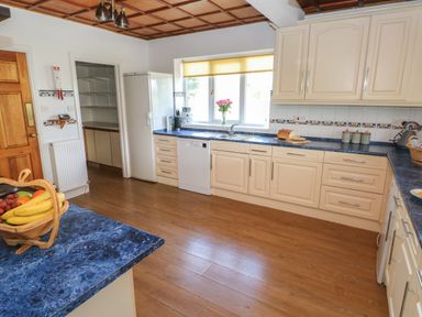 A kitchen with cream cabinets blue countertops wooden floor and a fruit basket at Hillside Lodge in Newtown