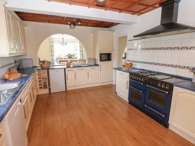 A kitchen with blue countertops white cabinets a blue stove and a dining area visible through an arched doorway at Hillside Lodge in Newtown