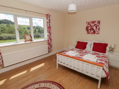 A bedroom with a double bed two bedside tables and a window showing greenery at Hillside Lodge in Newtown