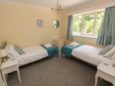 A bedroom with two single beds bedside tables lamps window and blue curtains at Hillside Lodge in Newtown