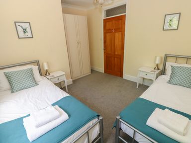 A bedroom with two single beds bedside tables lamps a wardrobe and a wooden door at Hillside Lodge in Newtown