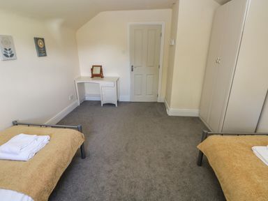A bedroom with two single beds a desk a wardrobe and a door at Hillside Lodge in Newtown