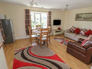 A living room with a dining table and chairs a sofa an armchair and a television at Hillside Lodge in Newtown