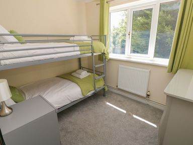 A bedroom with bunk beds bedside table lamp window and green curtains at Hillside Lodge in Newtown