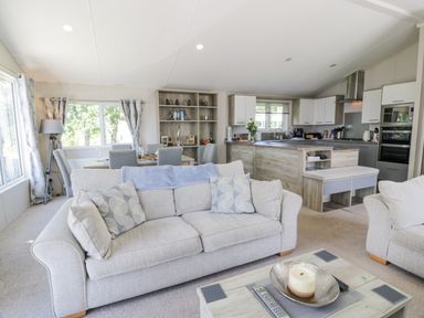 An open plan living room with sofas dining table bookshelf and kitchen at Olivia's Haven in Wemyss Bay