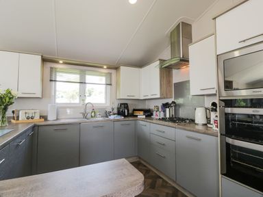 A kitchen with grey and white cabinets a window a toaster kettle and oven at Olivias Haven in Wemyss Bay
