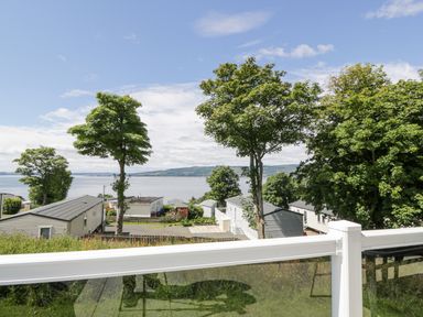 A view of trees and mobile homes overlooking a body of water at Olivias Haven in Wemyss Bay