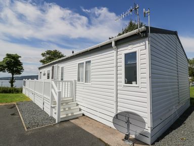A white mobile home with stairs and a railing outside near a grassy area and a tree at Olivias Haven in Wemyss Bay