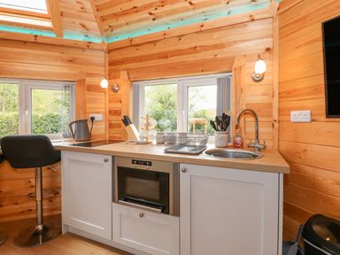 A kitchen area with a countertop sink oven and stools at Dragonfly Retreat in Upper Marham