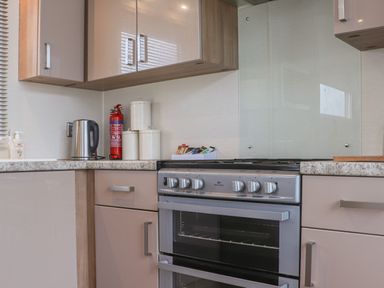 A kitchen corner with stove oven kettle fire extinguisher and canisters at Tiptoes Lodge Carnforth