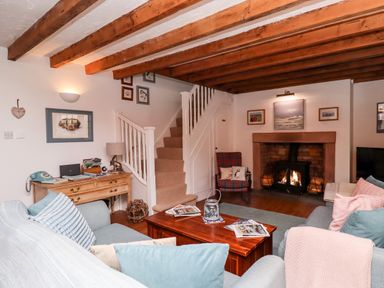 A living room with wooden beams a fireplace a wooden coffee table and a staircase at Seahares in Seahouses