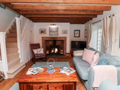 A living room with a wooden coffee table sofas a fireplace and a staircase at Seahares in Seahouses
