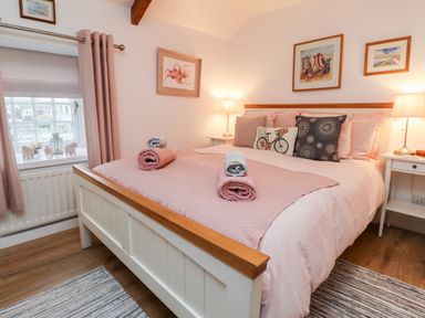 A bedroom with a bed with folded towels on it bedside tables with lamps and framed pictures on the walls at Seahares in Seahouses